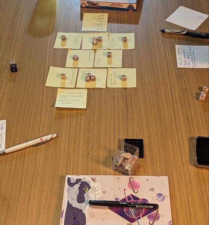 A TTRPG session in progress. Sticky notes in the middle of the table represent a starship and its various modules, with dice placed on top of them to represent available resources and power assignments.