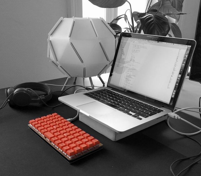 An ortholinear layout keyboard with orange keycaps on a desk